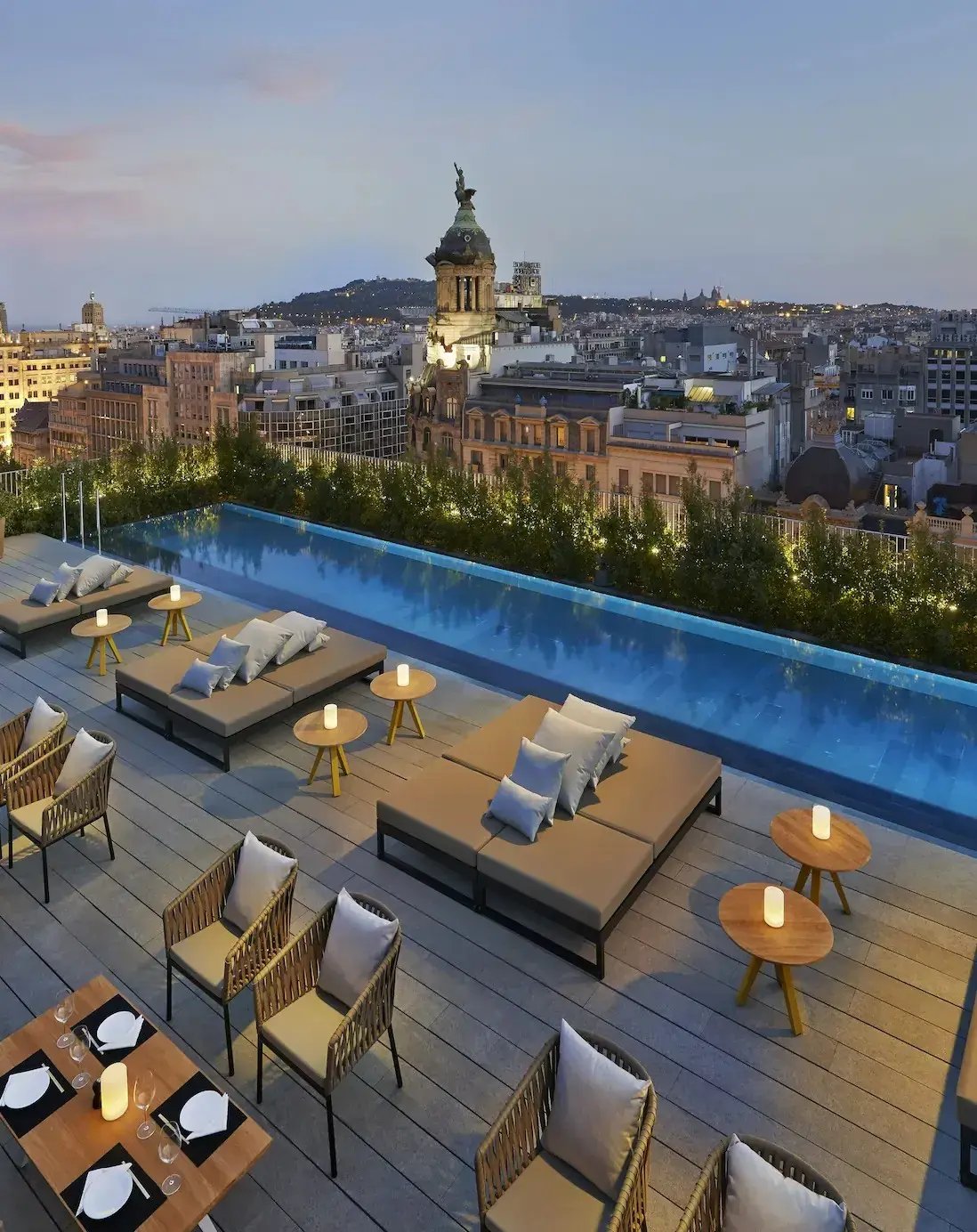 Dakterras en infinity-zwembad bij het Mandarin Oriental Barcelona, met uitzicht op de skyline van Barcelona bij zonsondergang.