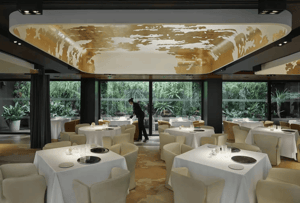Elegante eetzaal in het Mandarin Oriental Barcelona met prachtig gedekte tafels en uitzicht op de rustige tuin van het hotel.